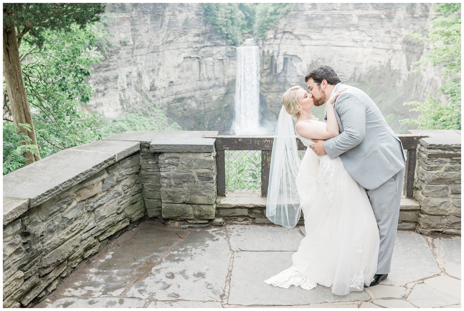 Wedding photo of bride and groom kissing by a waterfall at Taughannock Falls