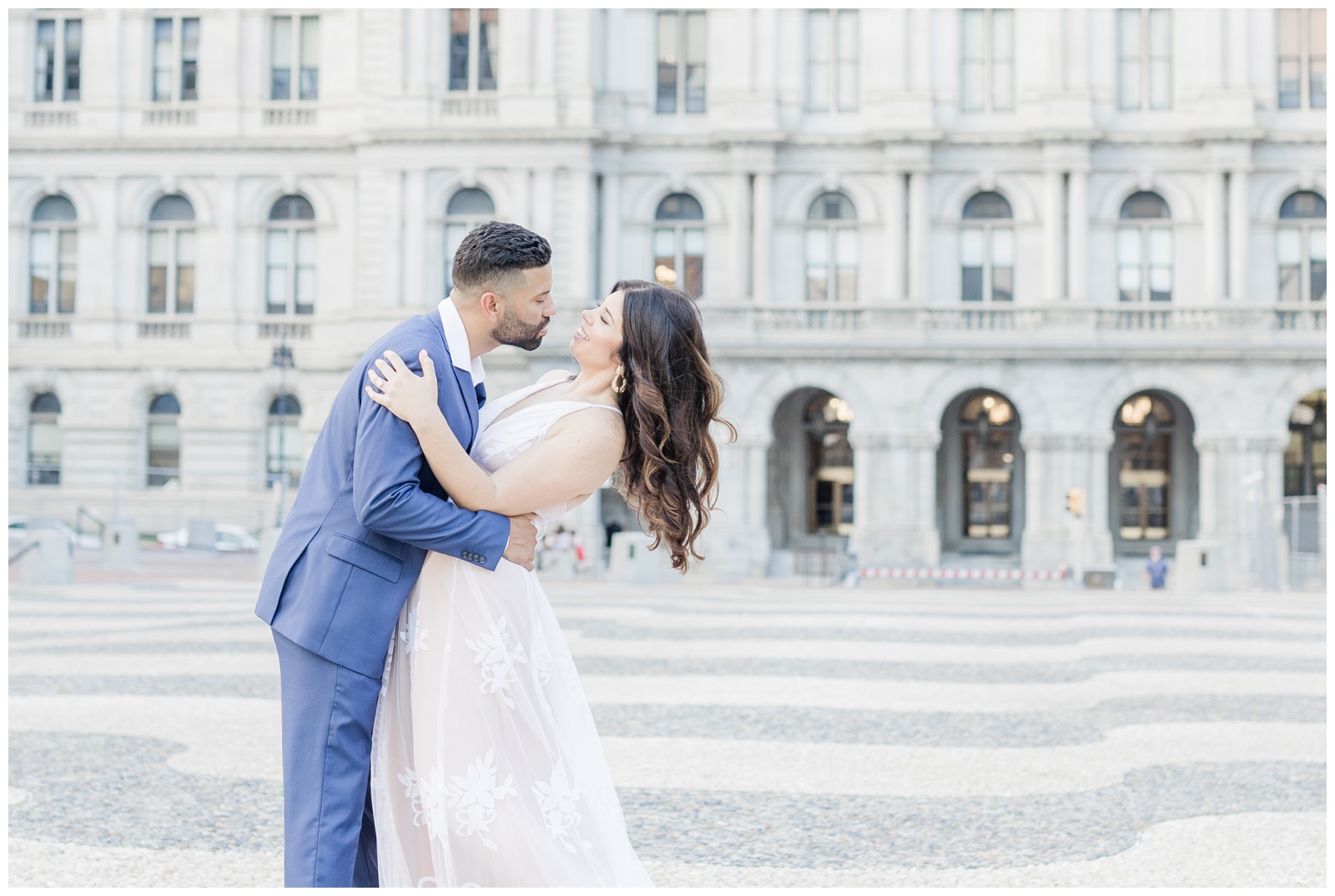 Engaged couple in a navy suit and a white dress in front of the capital building in Albany, NY