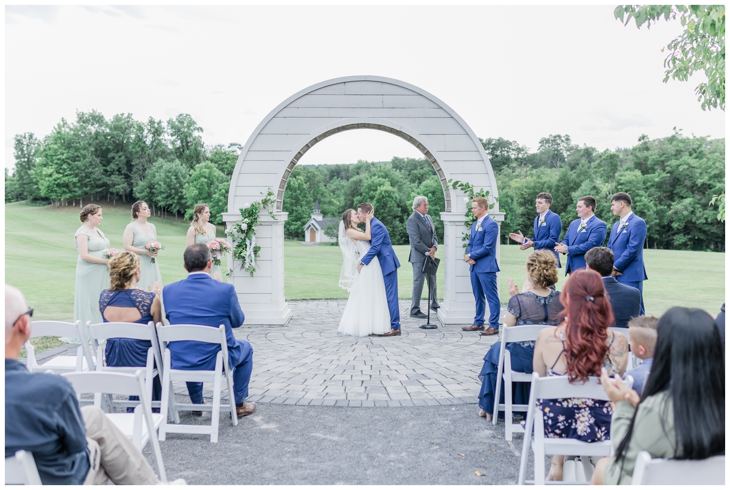 First kiss as husband and wife on their wedding day at Hayloft at the Arch. This beautiful outdoor barn wedding venue is perfect for intimate weddings and an elegant barn feel. Photographed in a light and airy style by Nicole Weeks Photography who is based in Albany, NY.