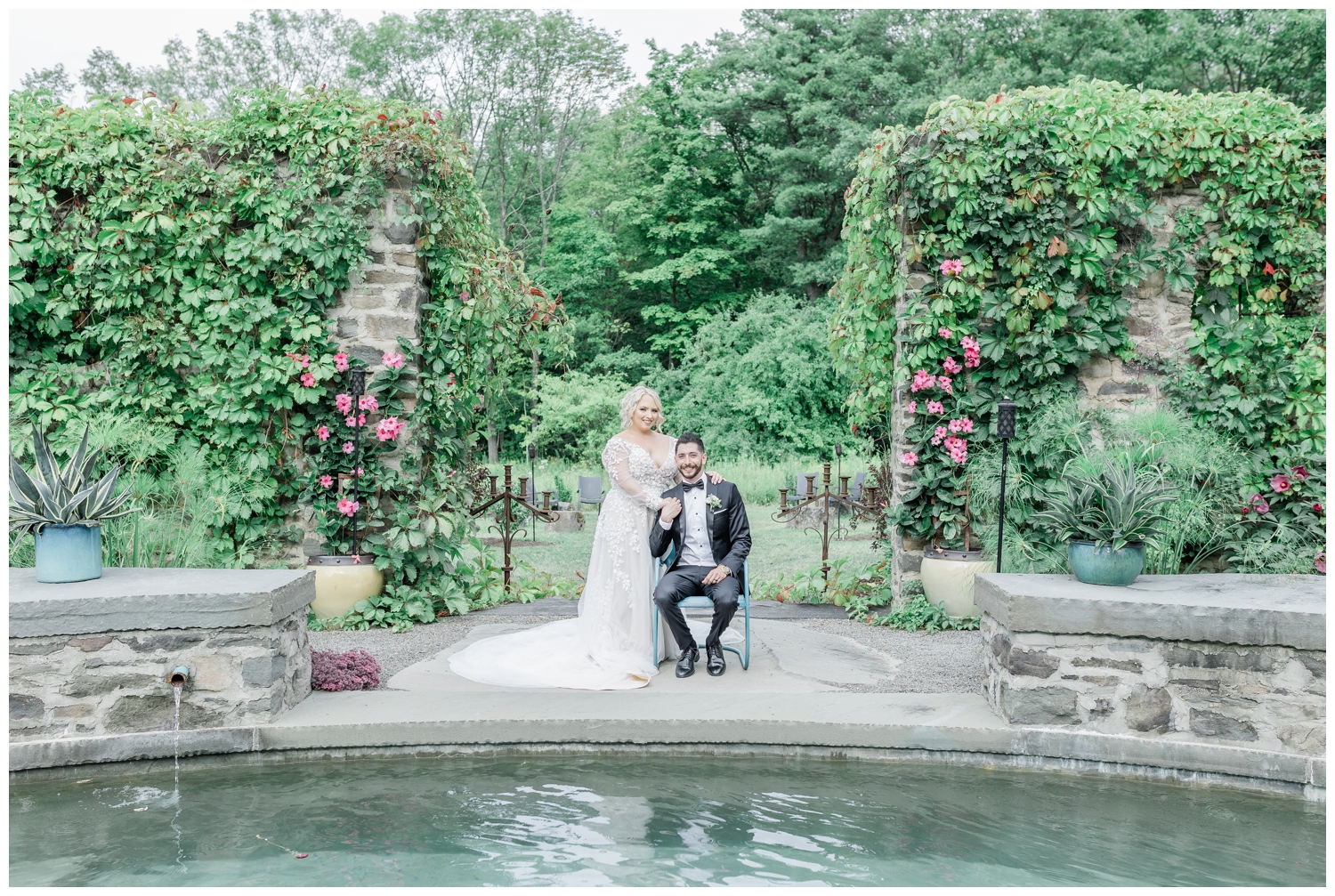 Classic and timeless photo of a groom sitting with his bride standing next to him in the middle of a garden in front of a pool. Their intimate wedding was celebrated at an outdoor venue near Ithaca, NY called The Treman Center. These images were photographed and edited in a light and airy style by Nicole Weeks Photography who is located in Albany, NY.
