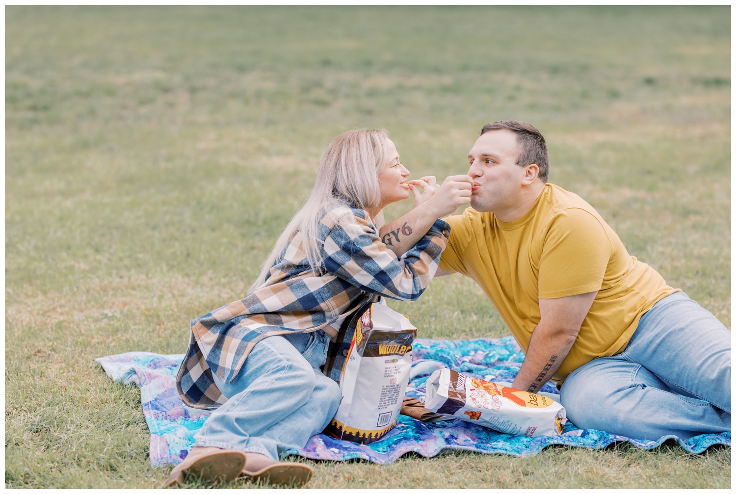 Couple sharing their favorite BBQ chips during their engagement session in Ballston Spa at a local park during the Fall season.