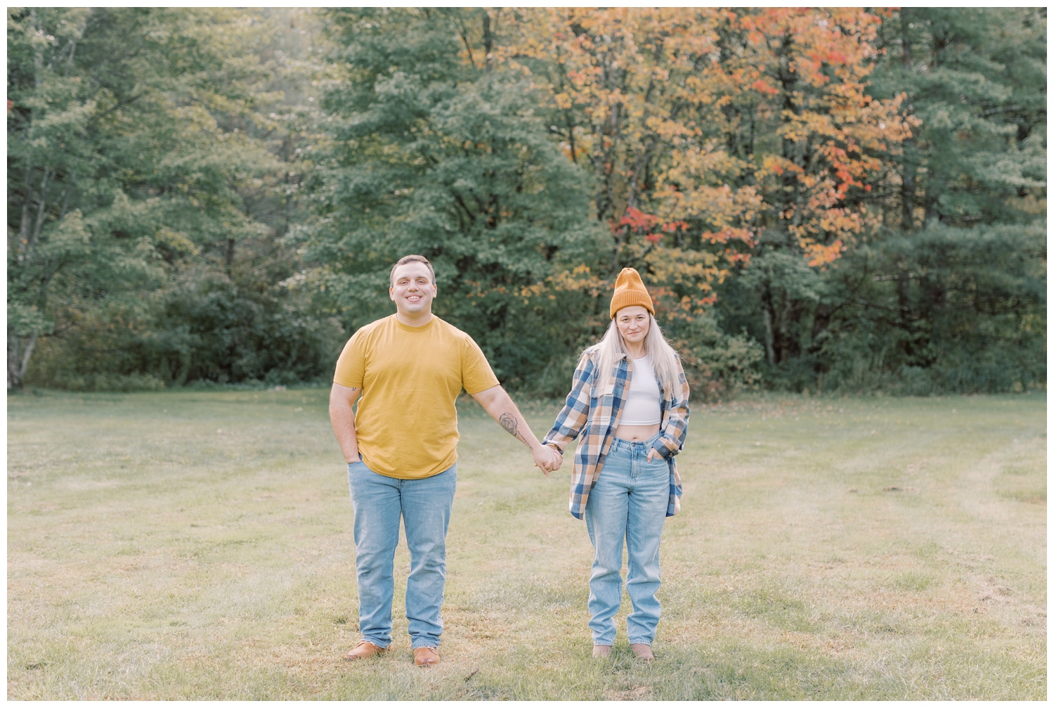 Couple holding hands and looking into the camera during their fall themed engagement session at Shenantaha Creek Park in Ballston Spa, NY.