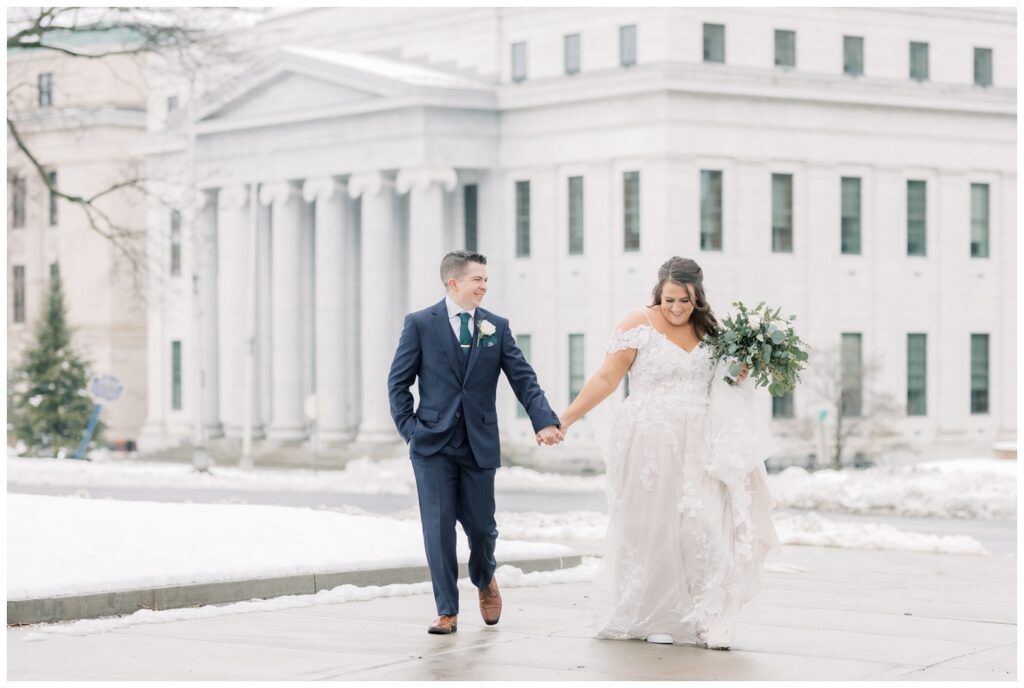 Bride and Groom holding hands during their Winter Elopement at Empire Plaza near the NY State Capital Building. This is an example image of one of the locations of 10 places to elope near Albany, NY.