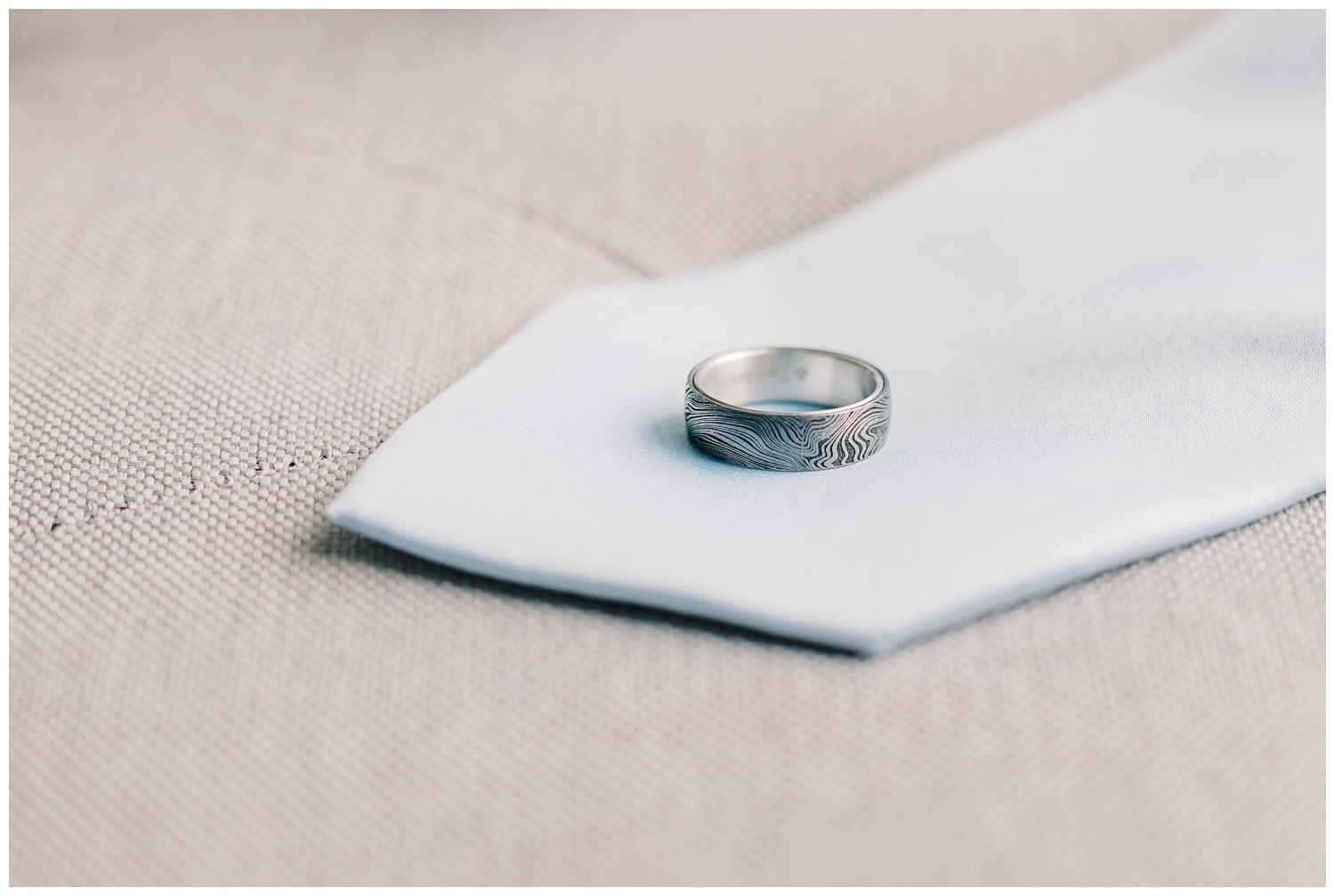 Groom's wedding band created by Brilliant Earth with a wooded texture on a light blue tie. 
