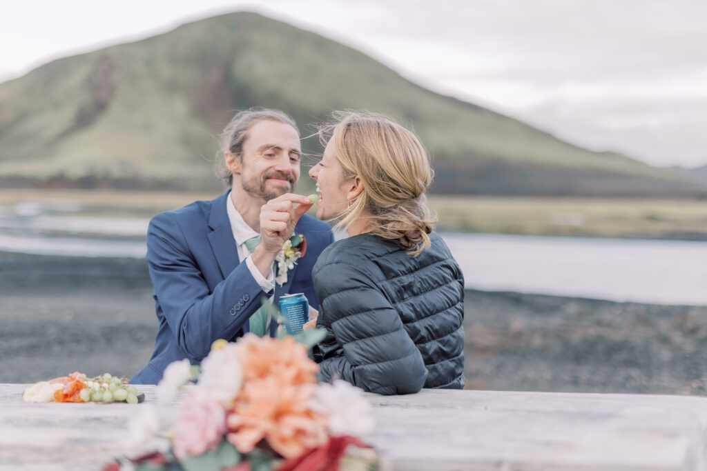bride and groom having a delicious picnic and feeding each other during their adventurous mountain elopement in the adirondacks
