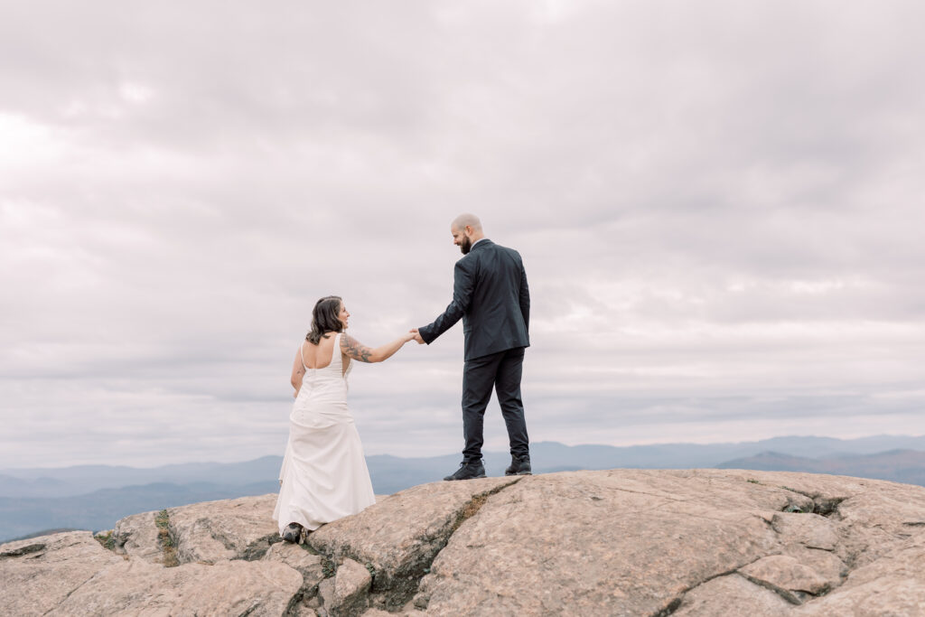 adventurous bride and groom elopement portrait hiking up a mountains in Adirondacks