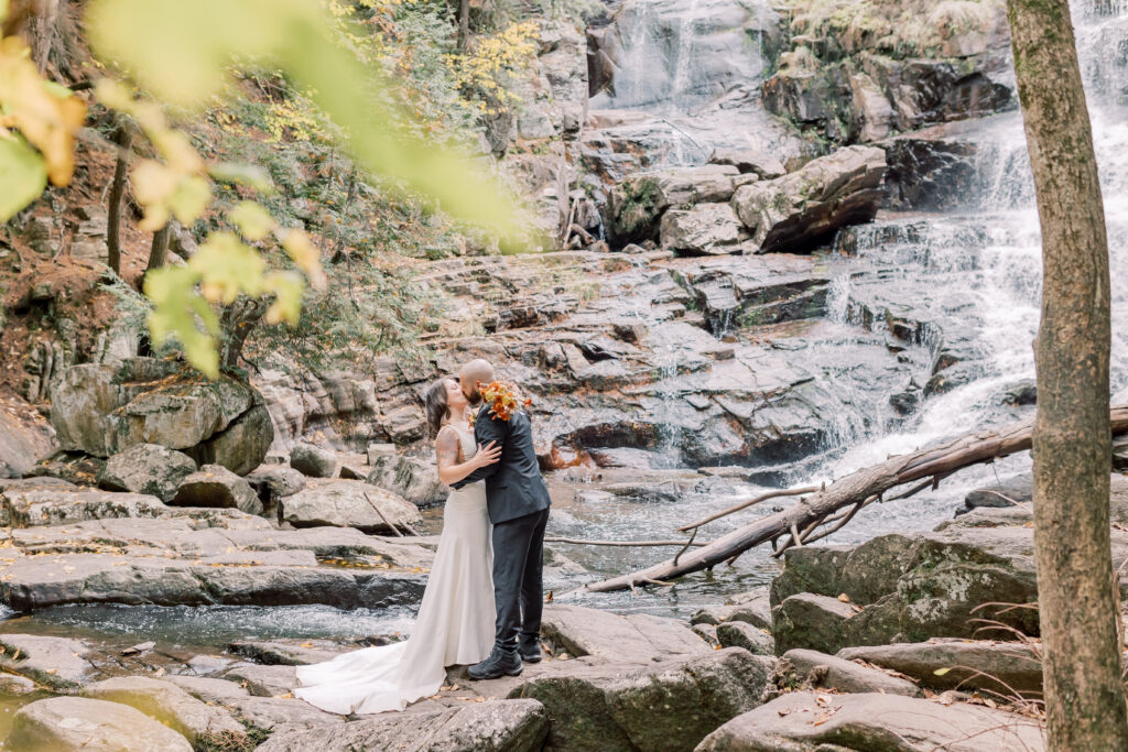 adventurous bride and groom elopement portrait in Adirondacks with waterfall in the backdrop