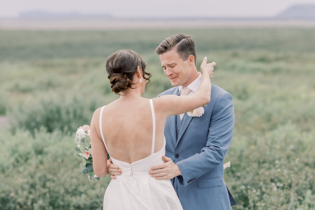 bride and groom emotional first look in a green, grassy field during their Adirondack elopement