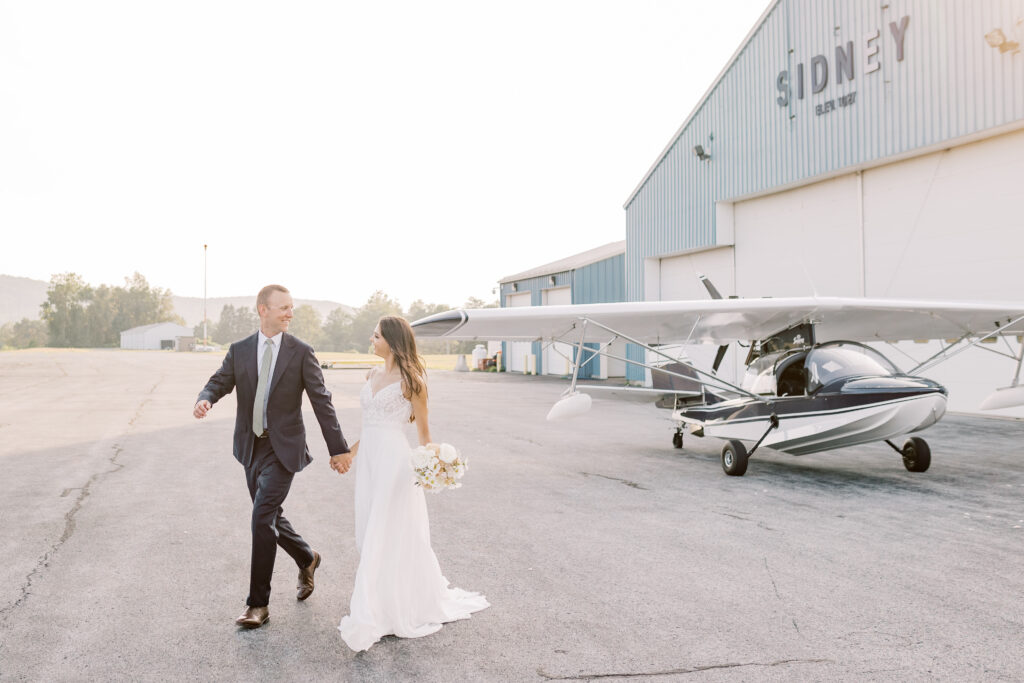 Bride and groom standing by a small plane, about to go on an adventure for their elopement day