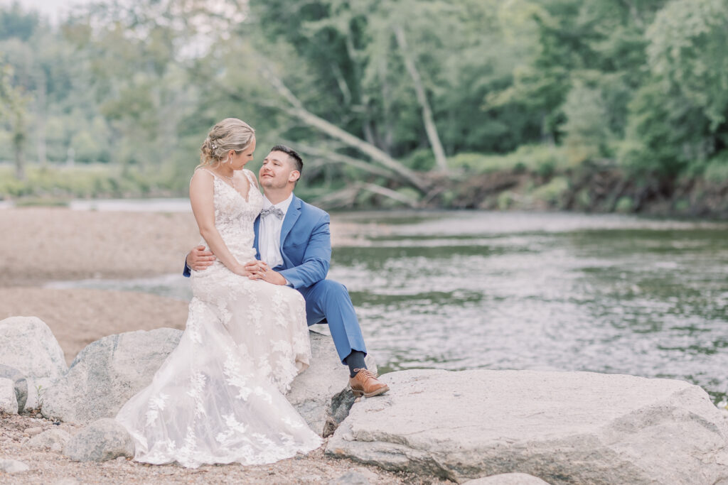 bride sitting in groom's lap by a beautiful lake in Adirondacks