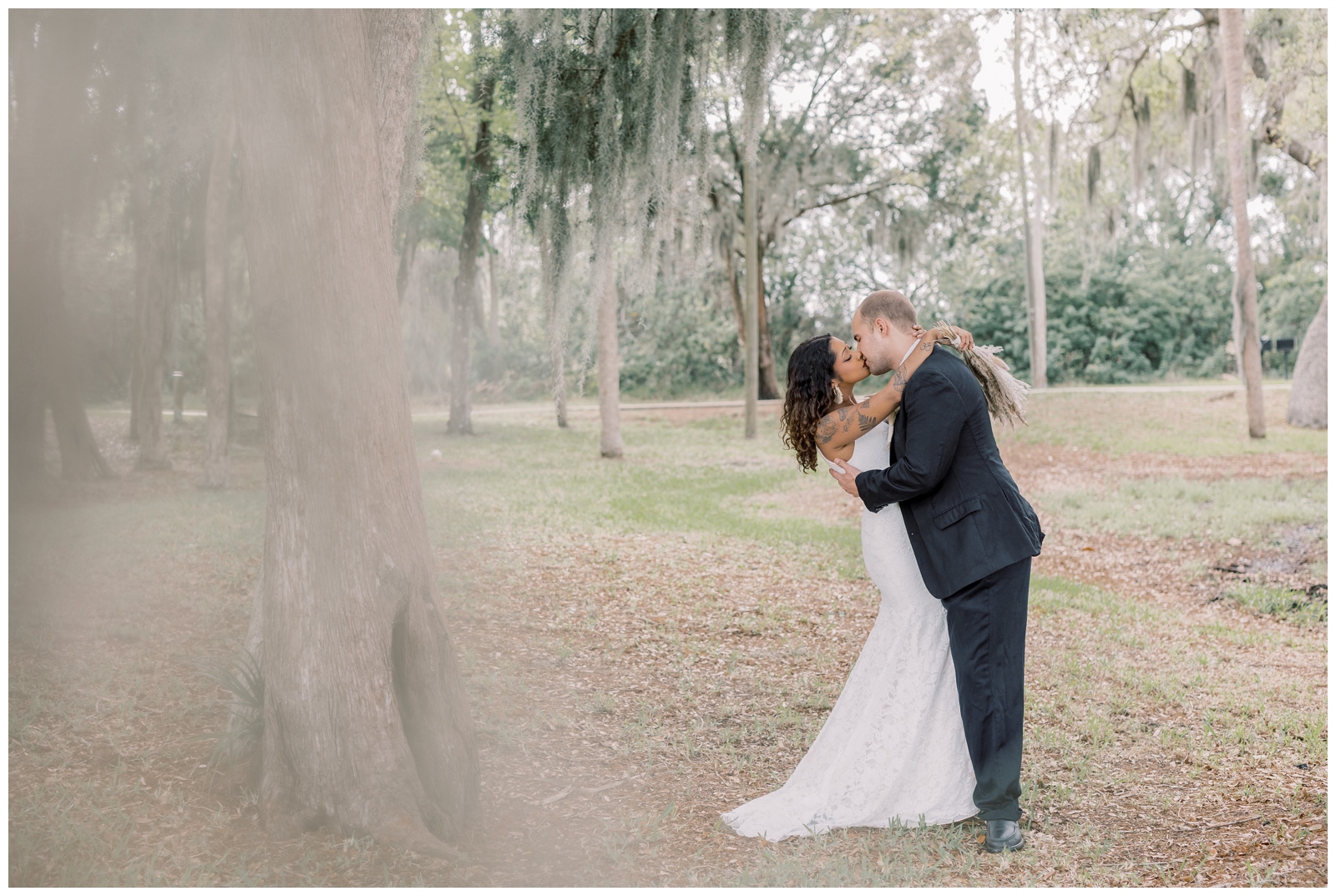 Couple kissing in a park in Crystal River Florida with Spanish Moss trees in the background.