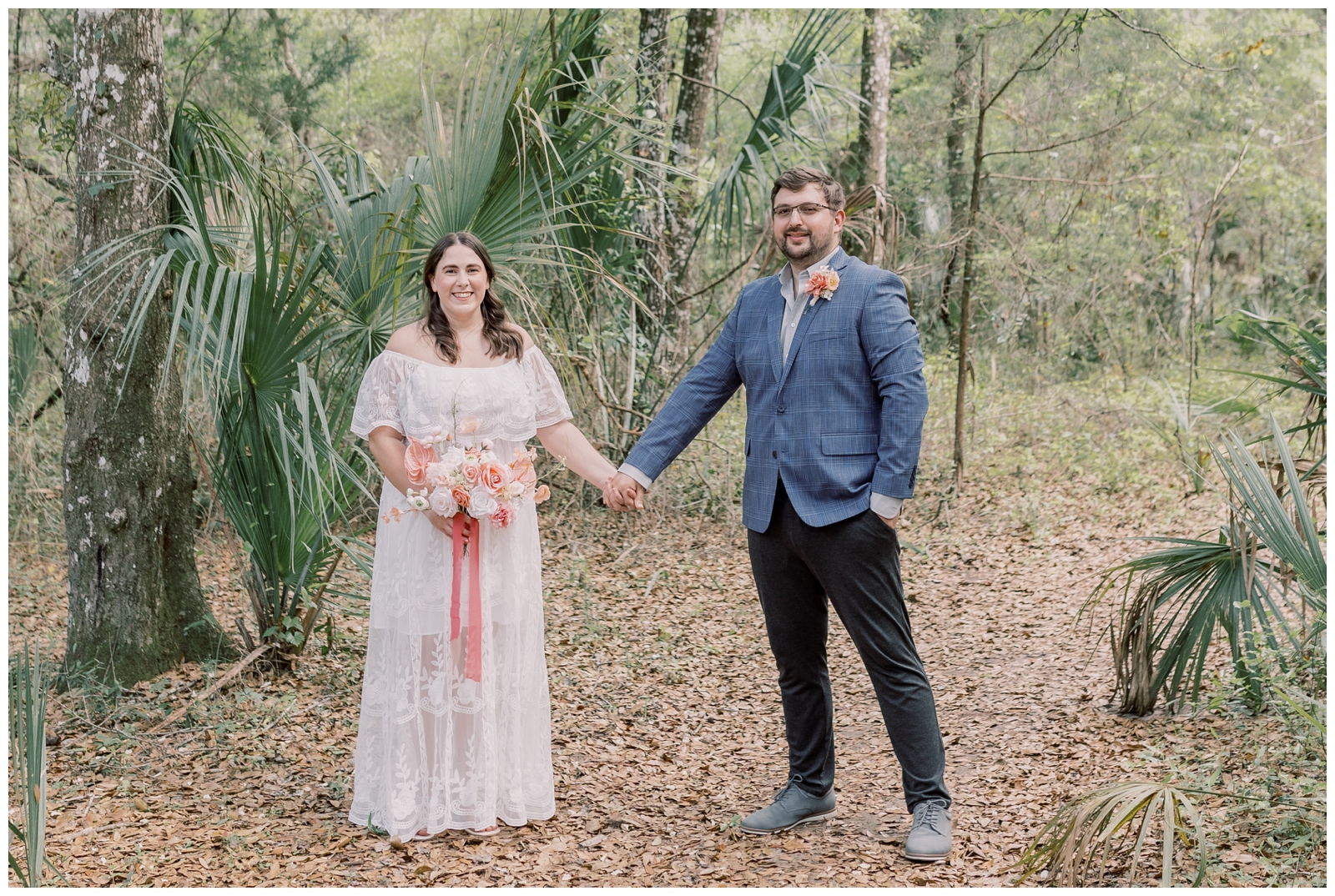 Couple holding hands and smiling in the park surrounded by Florida foliage on their wedding day.