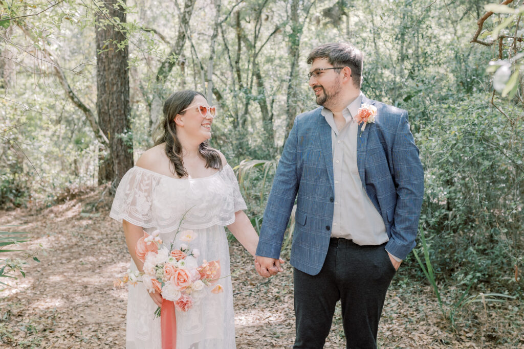 bride and groom walking hand in hand through forest