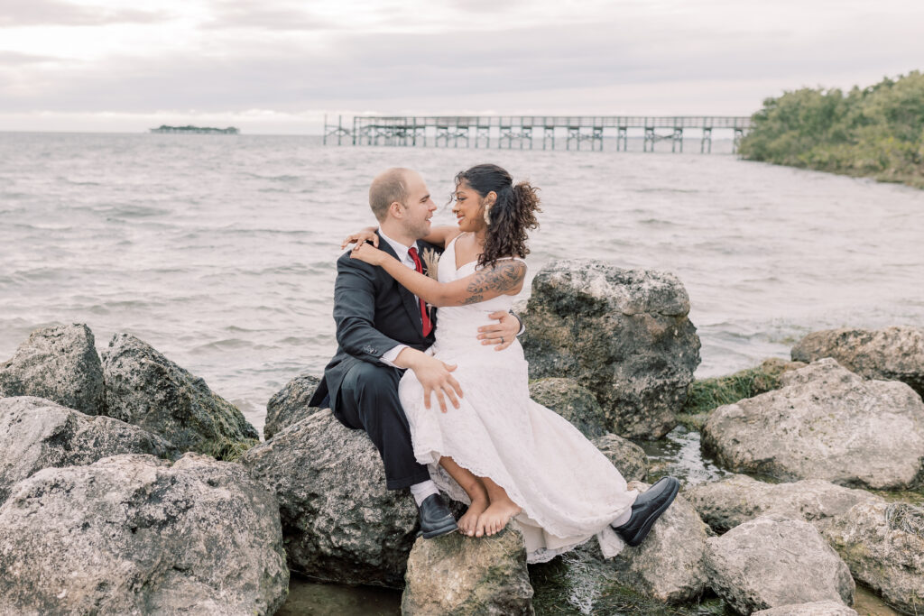bride and groom sitting on the rocks by Crystal River, Florida