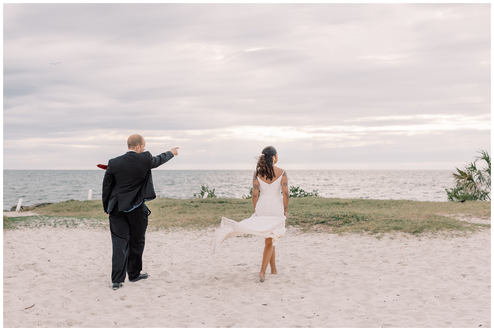 Couple looking out at the water on their wedding day on a sandy beach in Florida.