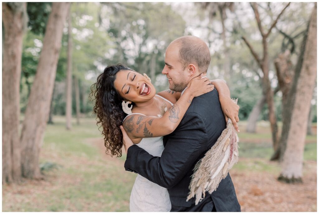 Black bride laughing while groom is holding her close and smiling at her.