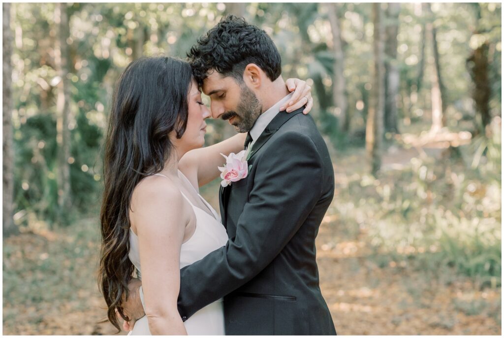 Couple hugging and pressing foreheads together in wedding attire. 
