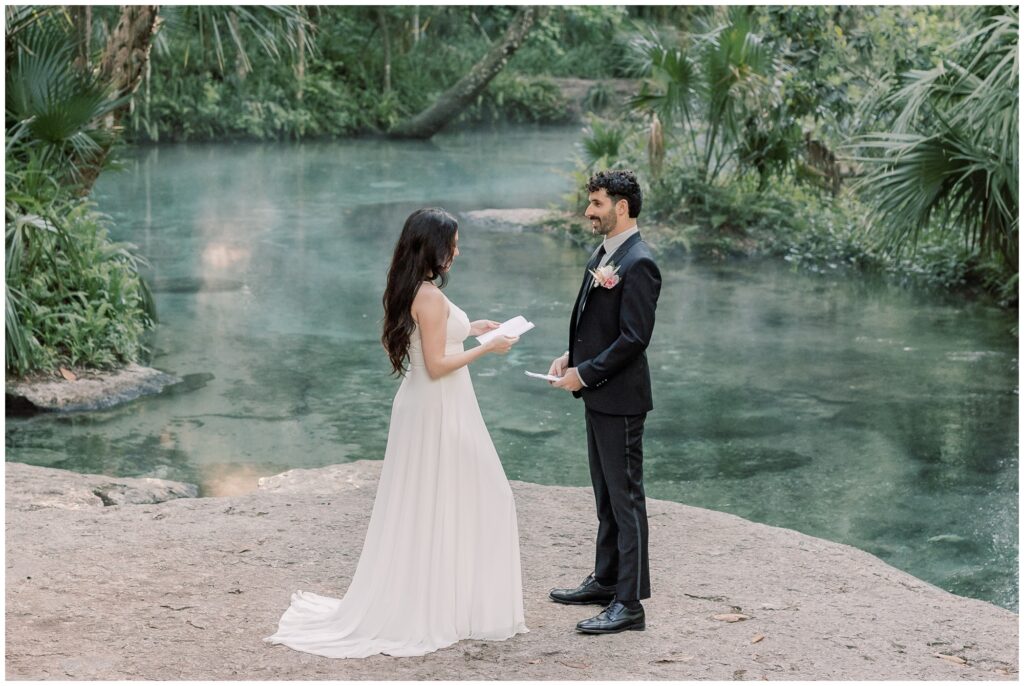 Bride and groom standing by a Spring in Florida reading their vows to each other.