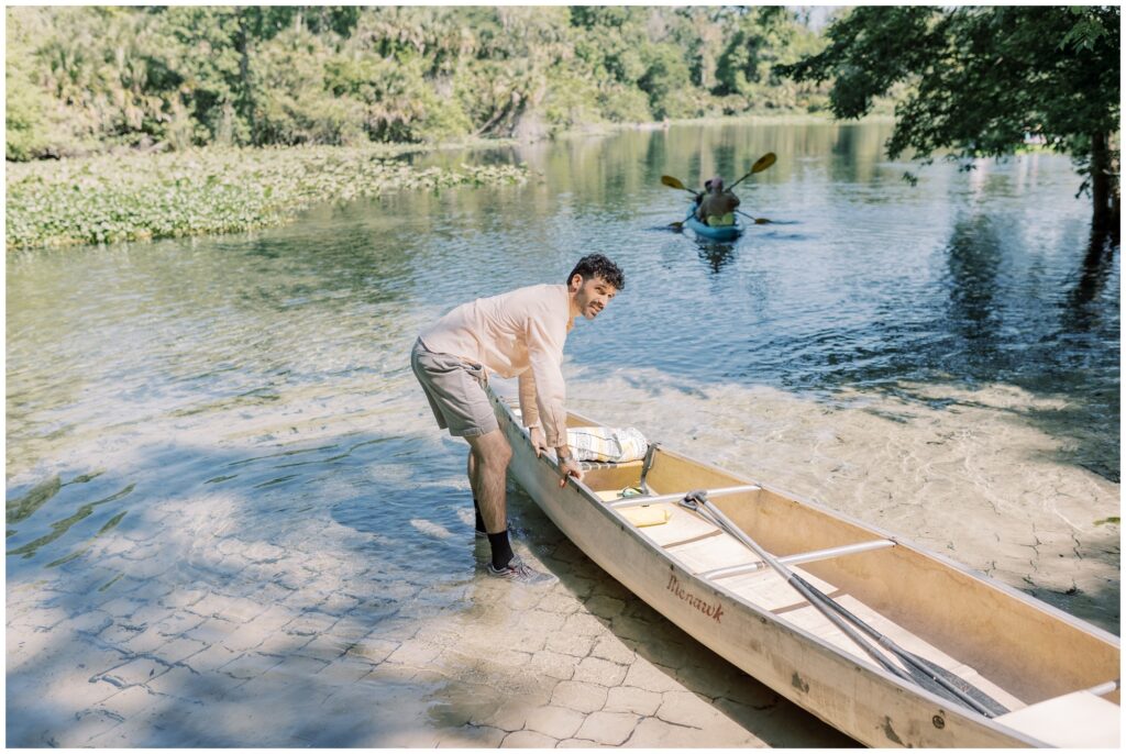 Man pulling a canoe into the water for his bride on their wedding day in Florida. 
