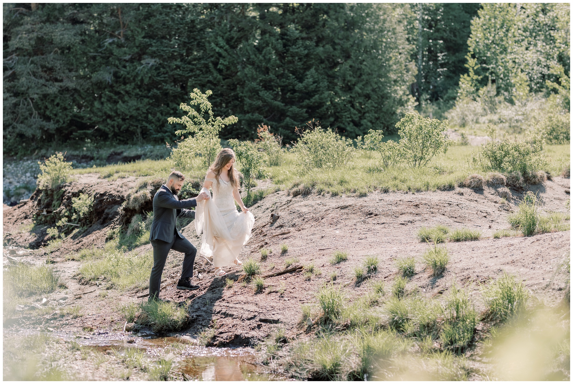 A groom helping his bride cross a stream on their adventure elopement. 
