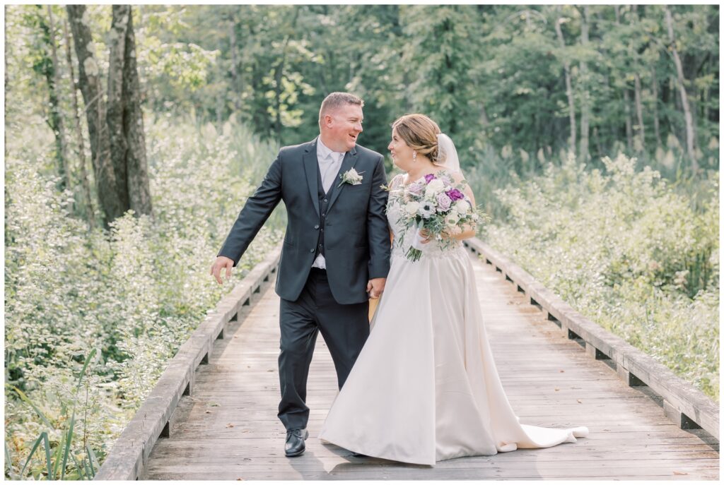 Bride and groom walking through the woods on a boardwalk in the Adirondacks near Saratoga, NY.
