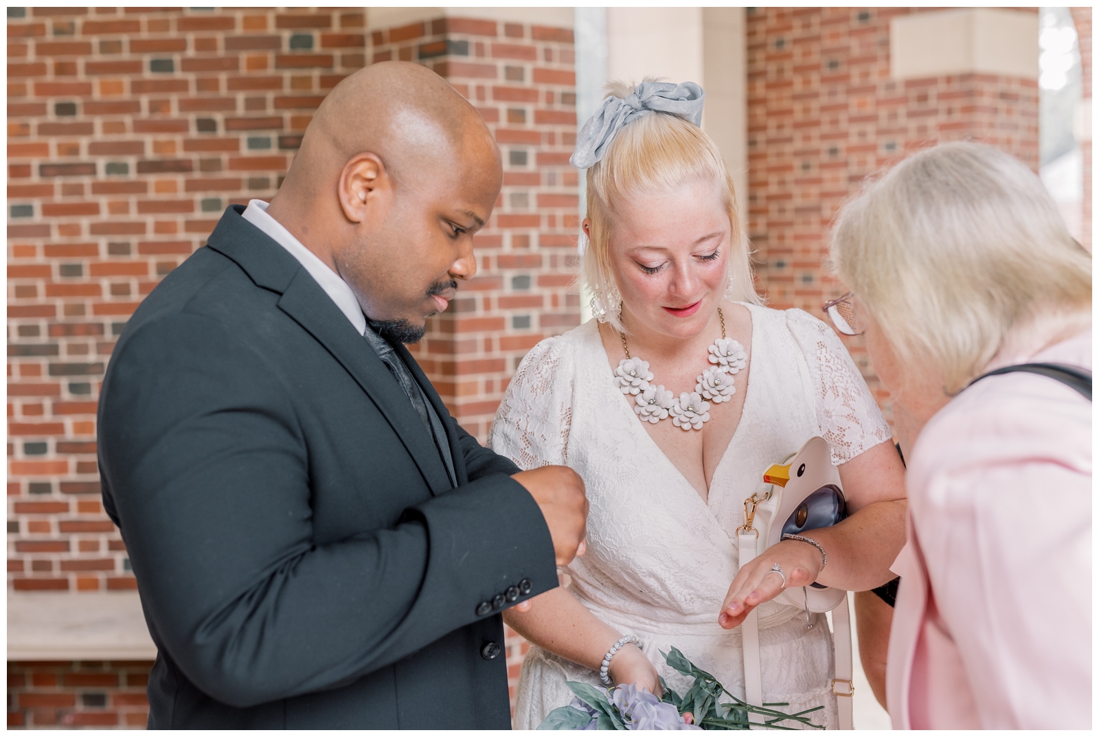 Interracial couple showing off their wedding bands to their family.
