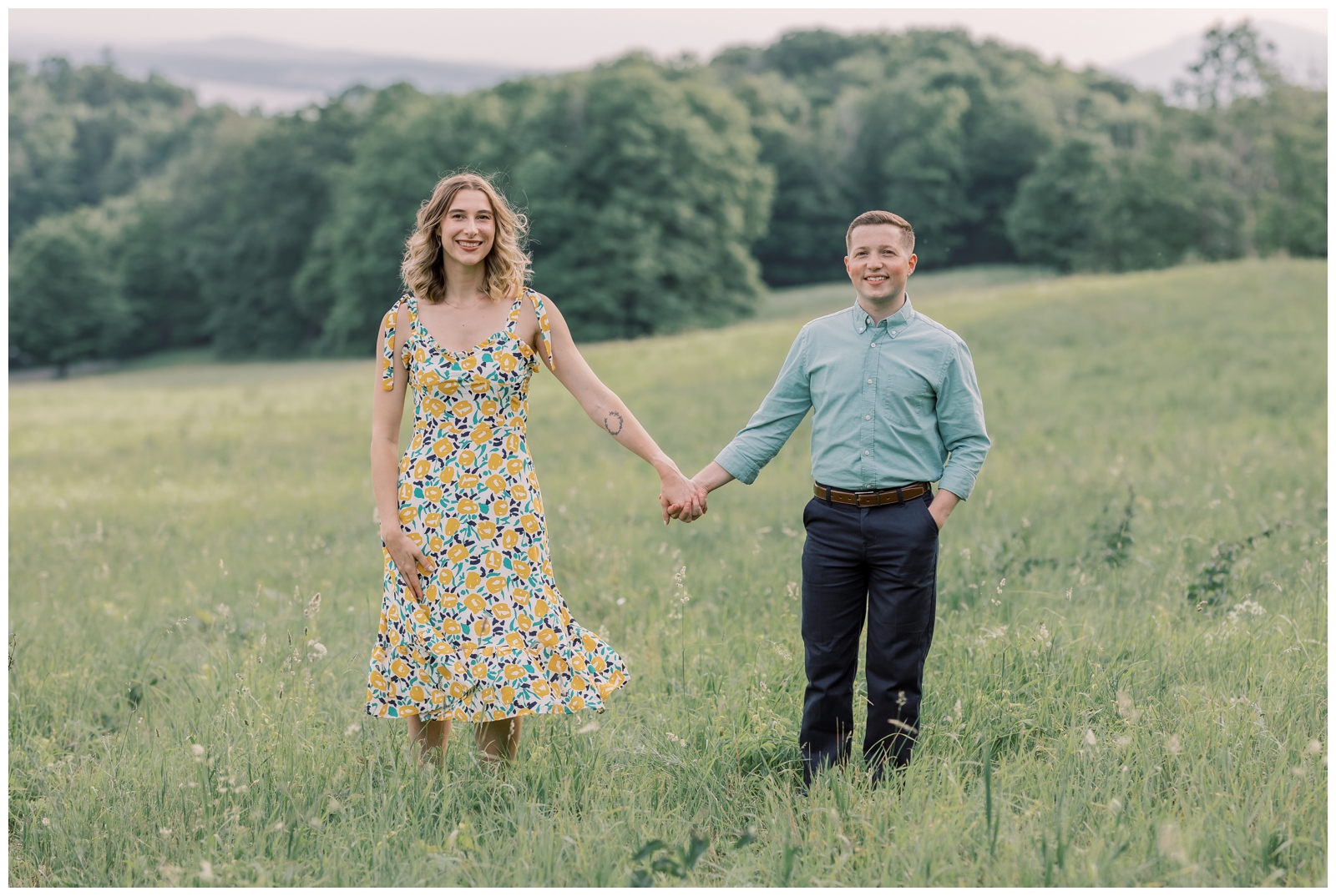 Man and Woman holding hands in a tall grassy field during their Spring engagement session in the Hudson Valley.
