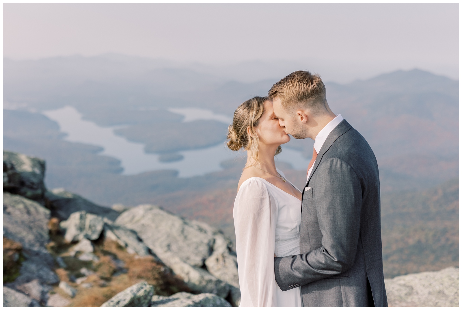 Bride and Groom kissing on a mountain overlooking Lake Placid.
