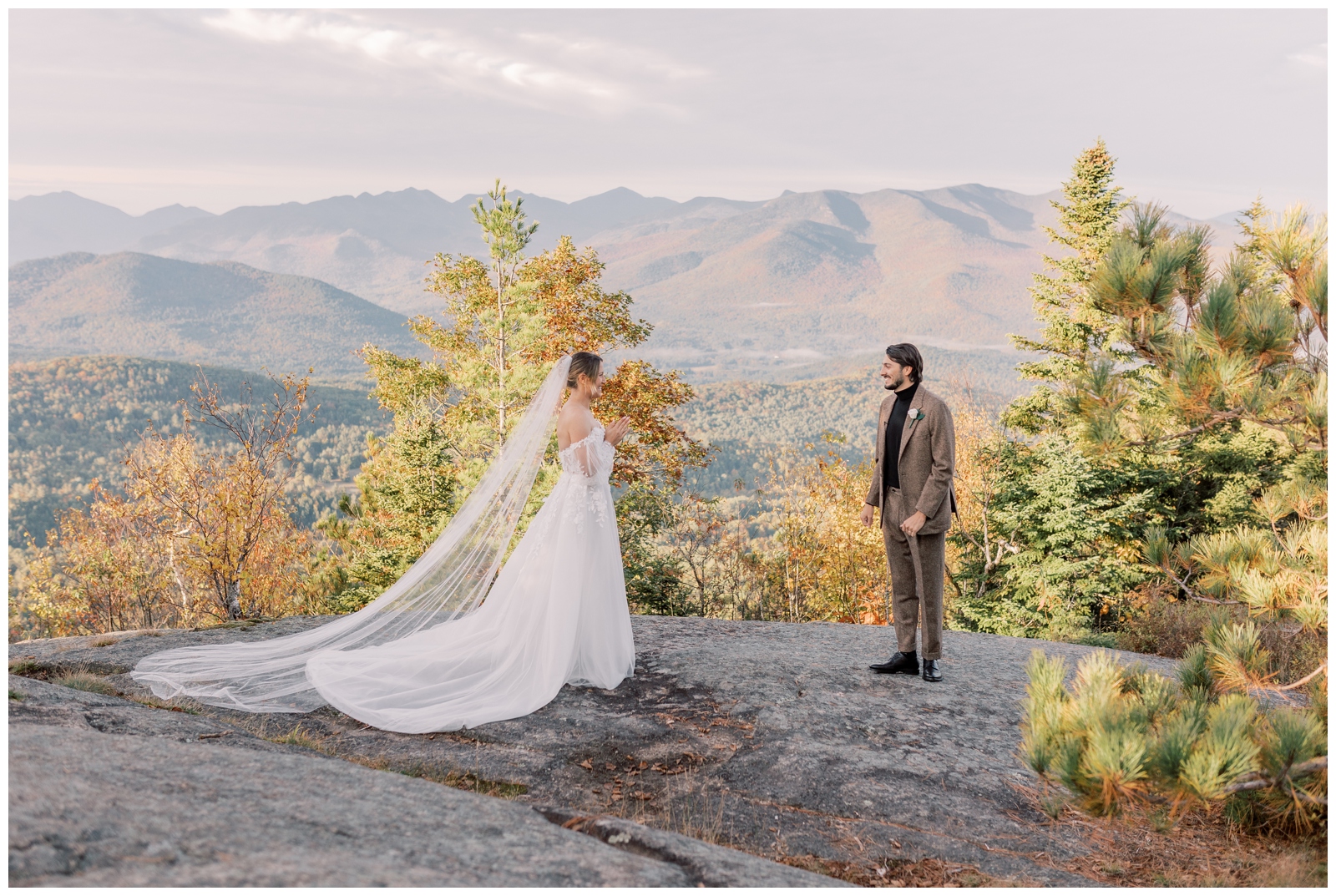 Groom in a brown suit sees his bride for the first time on their wedding day. This couple is standing on top of a mountain during the Fall at sunrise.
