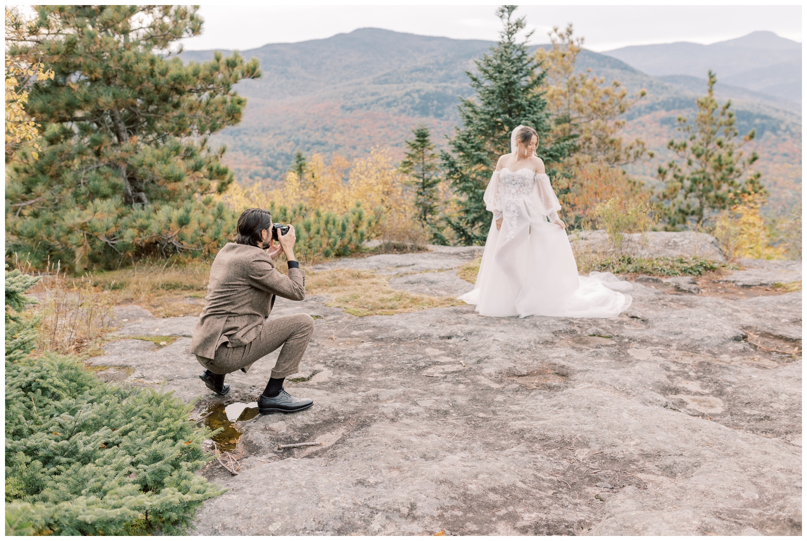 Man in a brown wedding suit taking pictures of his bride who is wearing a flowy boho inspired dress.
