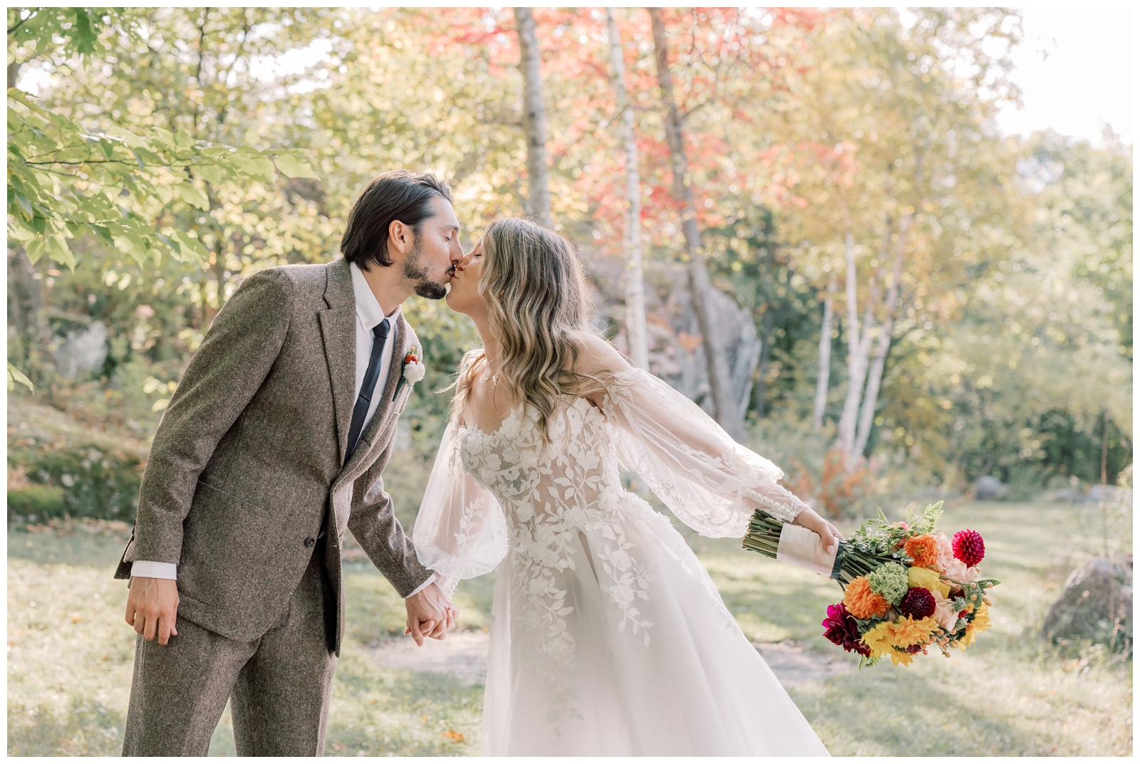 In a sea of colorful trees a brie and groom kiss.