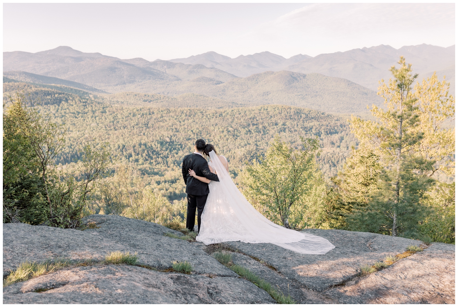 Bride and groom hugging while looking out at a mountain landscape in Lake Placid, NY.
