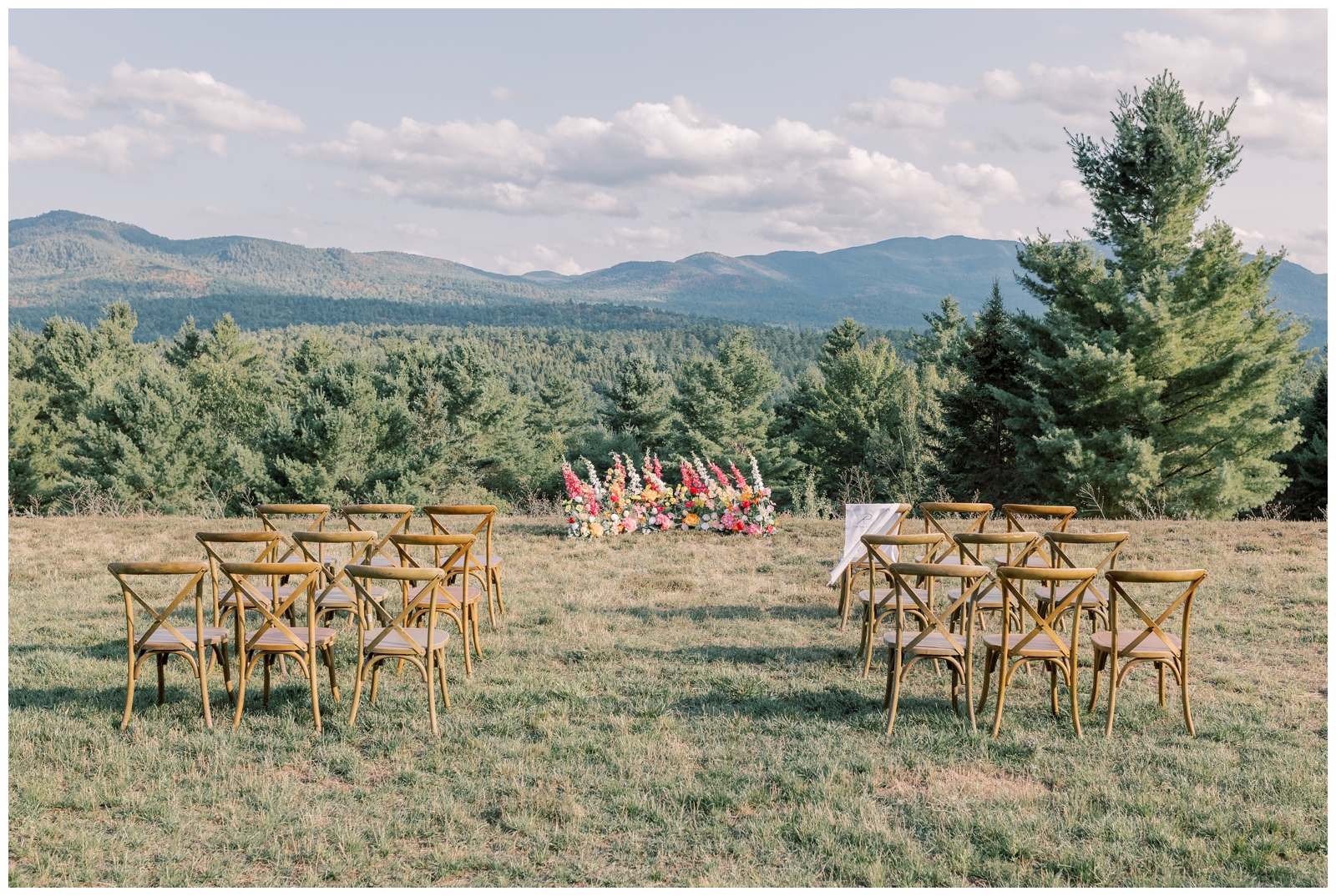 Ceremony set up in a field with a mountain view in the background.
