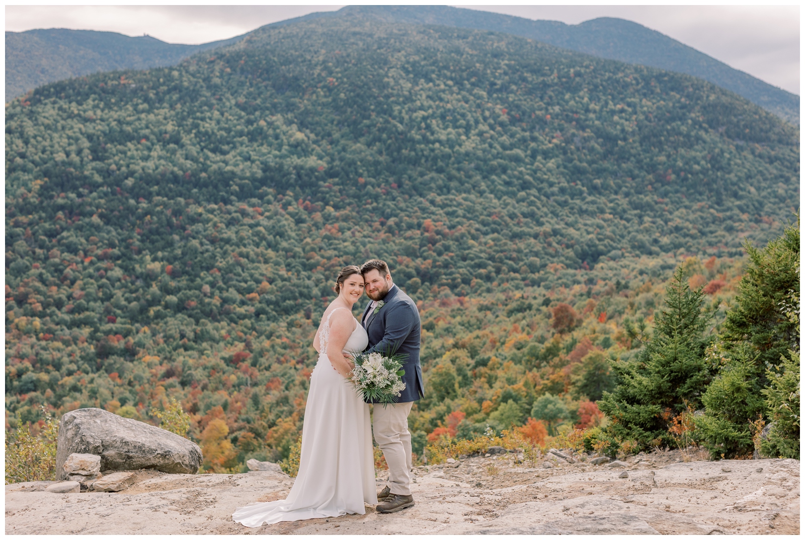 bride and groom posing on a mountain during their fall foliage elopement in the Adirondack mountains.